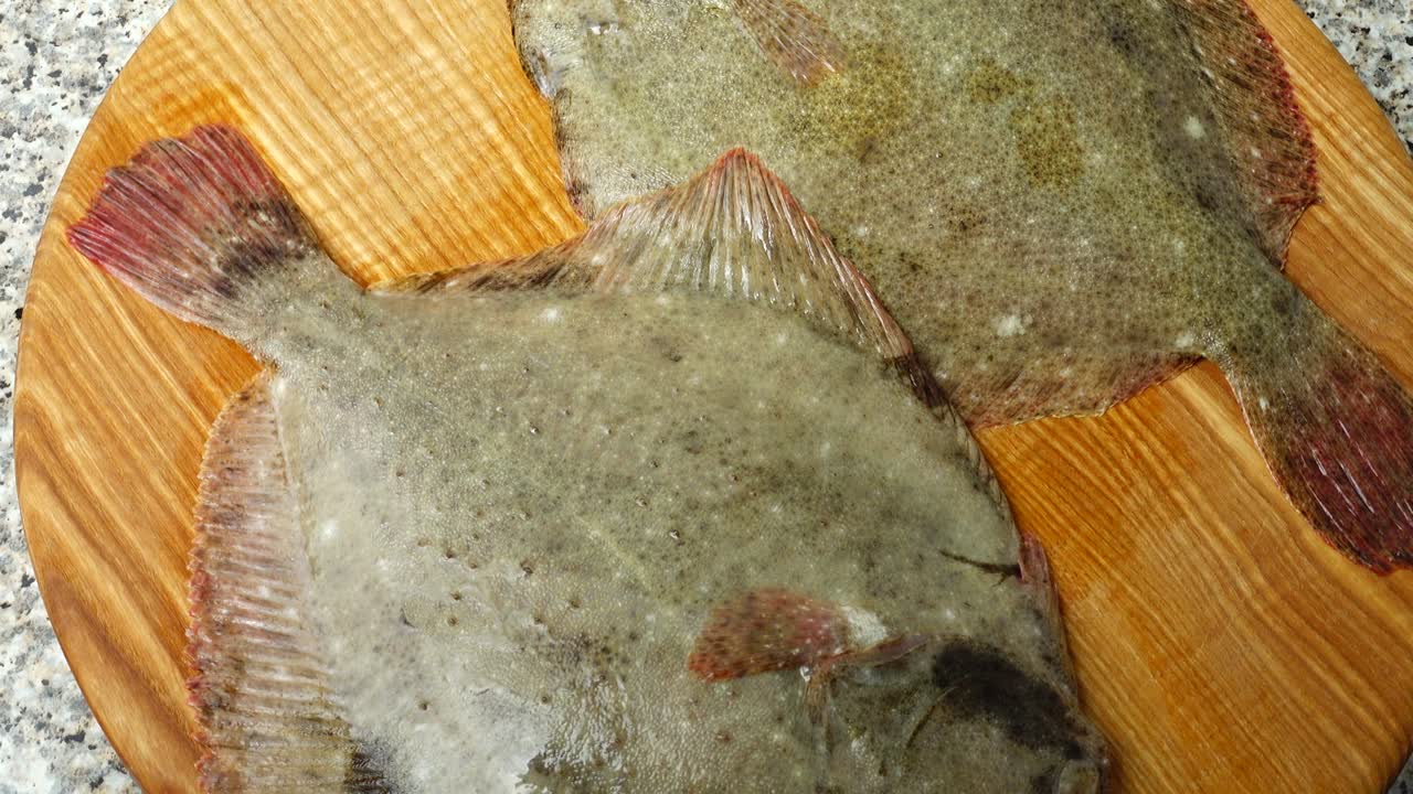 Fish of flatfish on a cutting board. Shooting in the movement