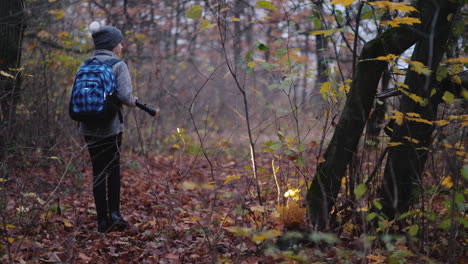 un niño con una cartera detrás de él camina por un bosque oscuro con una linterna se pierde en el