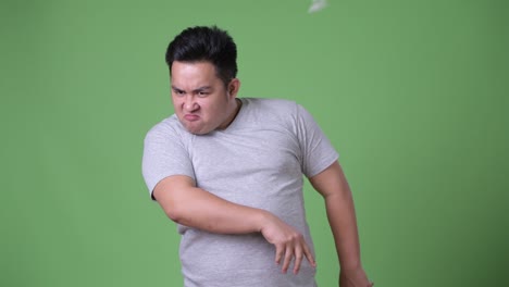 young handsome overweight asian man against green background