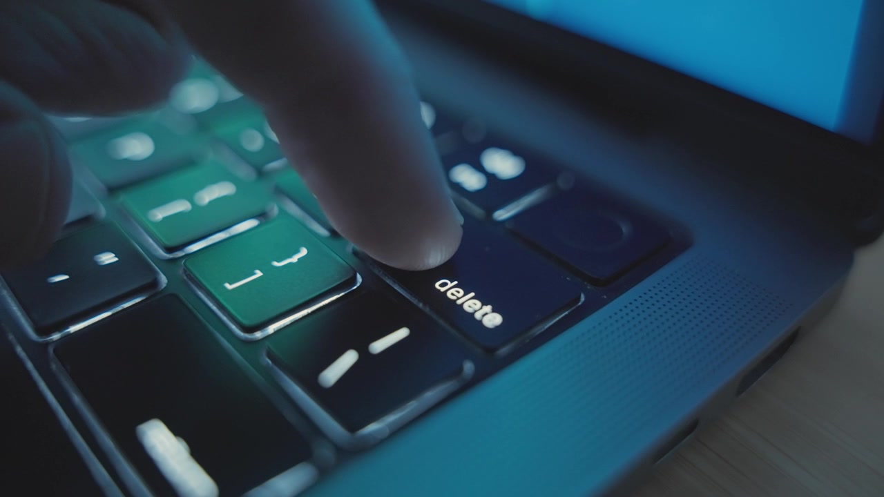 Close up of various clicks on Delete key or button on laptop keyboard at night. Hacker or programmer pressing to erase and delete action or grammar mistake. Undoing removing important data or email