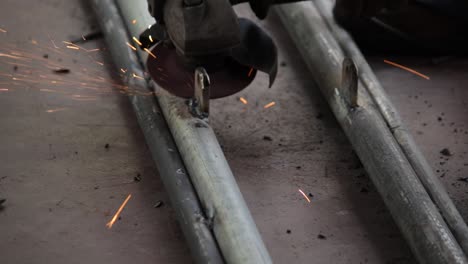 remove excess weld metal in iron pipes and get the smooth finishing of the welding, using an electric hand grinder by the handyman outdoor slow-motion clip