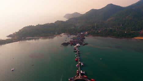 wide birdseye view of the bridge of koh chang in turquoise water with foggy mountains in background, travel destination, copy space, zoom out aerial