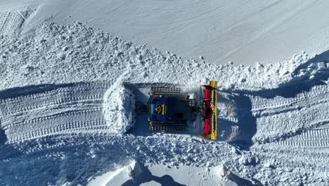 top down aerial view of snow groomer in ski resort, working on sunny winter day