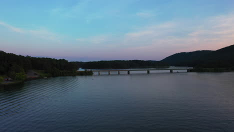 forwards fly above water surface, heading towards road bridge over lake allatoona