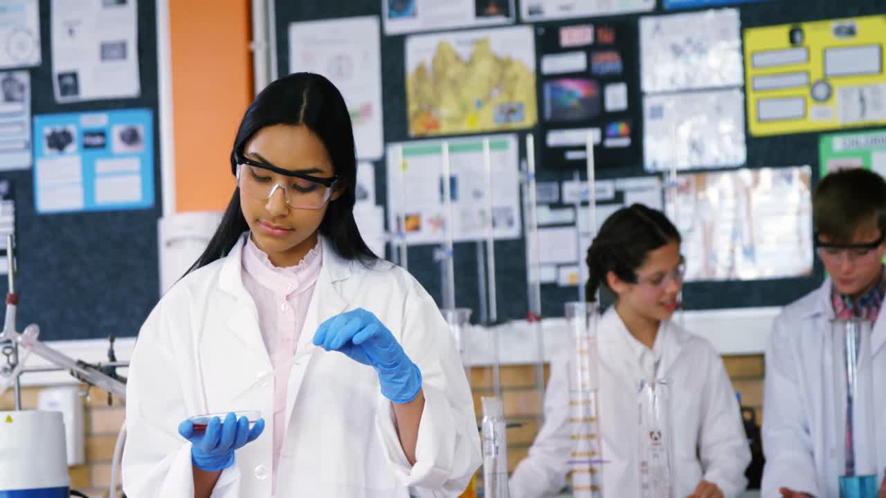 niña de escuela experimentando con productos químicos en el laboratorio de la escuela
