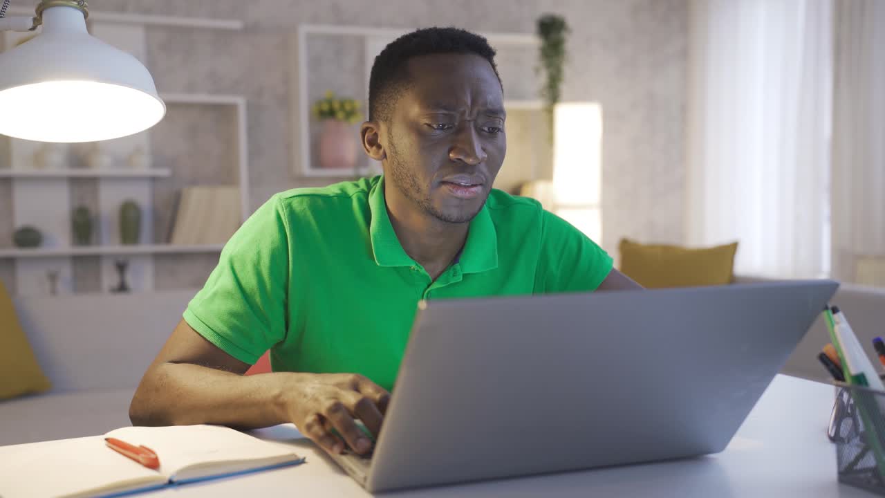 pensativo serio joven hombre de negocios afroamericano sentado en el escritorio de la oficina en casa con una computadora portátil pensando ideas de solución