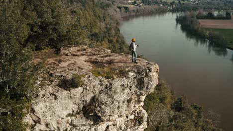 drone shot of woman on cliff edge by river