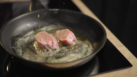 pork being seasoned and fried in a pan