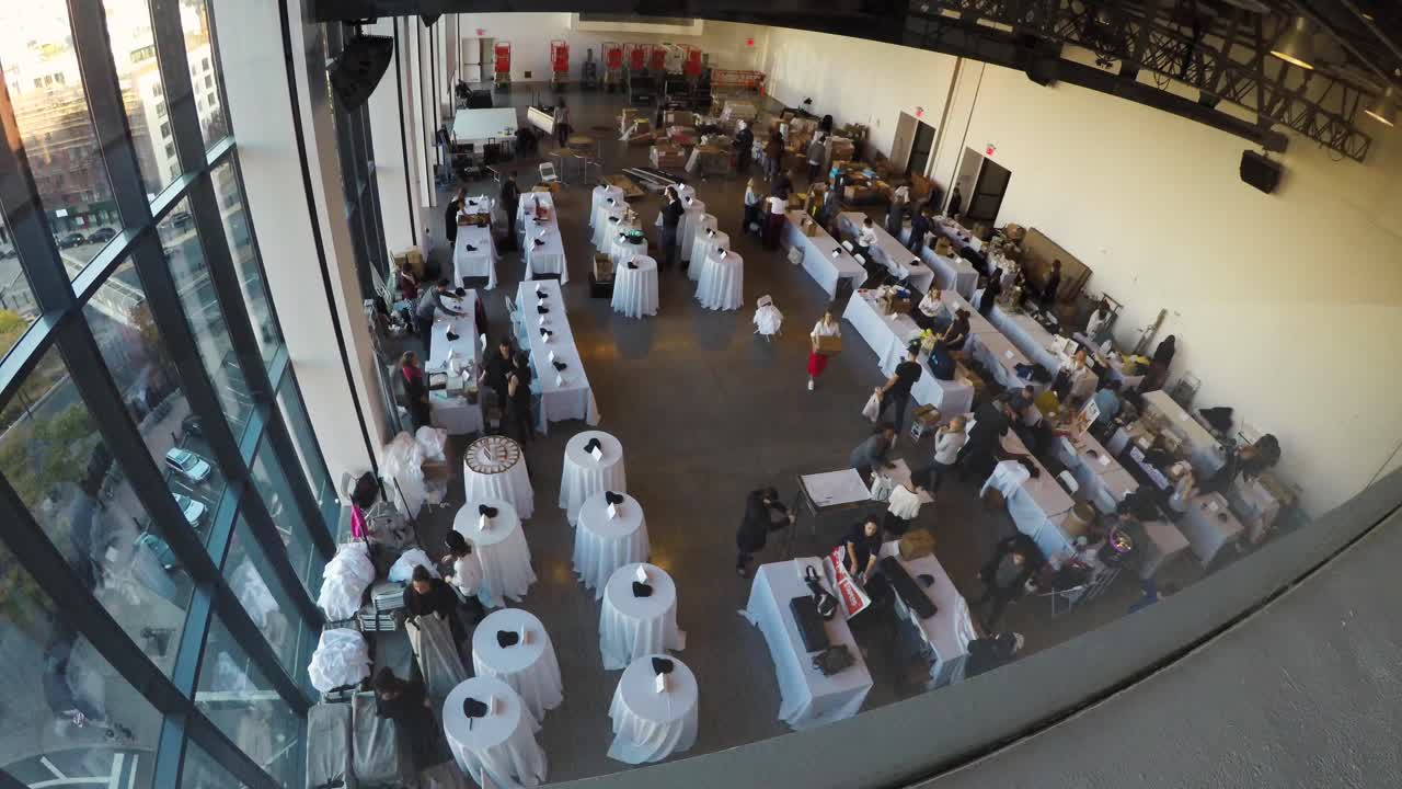 timelapse de 4.000 personas en una pequeña feria comercial instalando sus stands en un estudio de nueva york, desde una ventana del segundo piso en el lado izquierdo del edificio