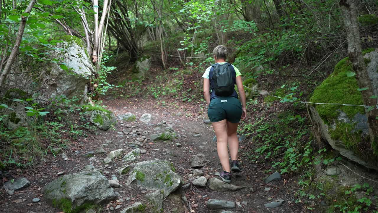 Mujer caminando por el sendero del bosque