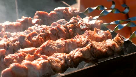 appetizing juicy pork barbecue is roasted on skewers on top of charcoal grill. close-up meat pieces.