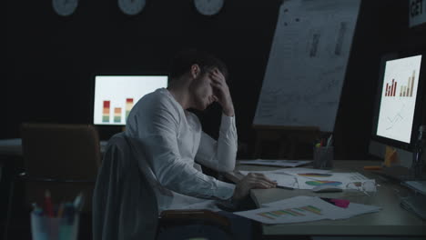 overworked businessman throwing document paper with economic data in office table