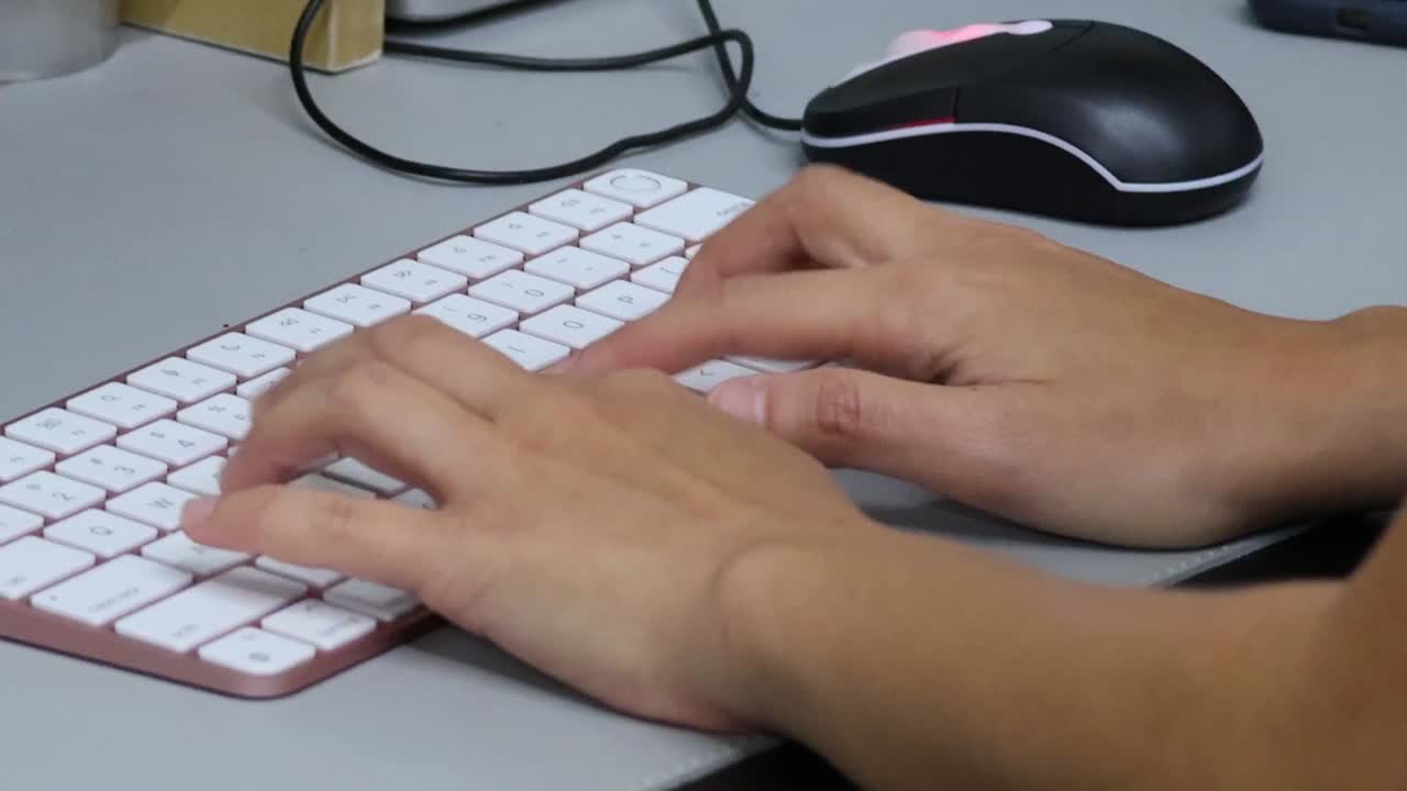 A close-up shot of a person's hands typing quickly on a white wireless computer keyboard