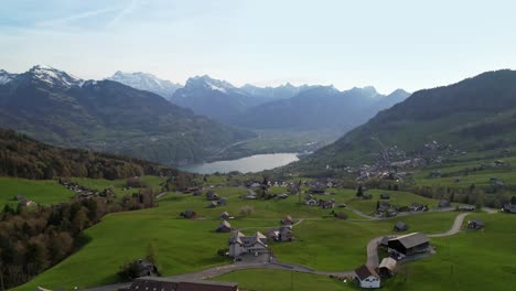 Vista-Aérea-Del-Pintoresco-Pueblo-Alpino-Con-Un-Lago-Con-Forma-De-Espejo