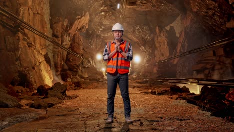 full body of asian male engineer with safety helmet pray for something while standing in underground mine tunnel
