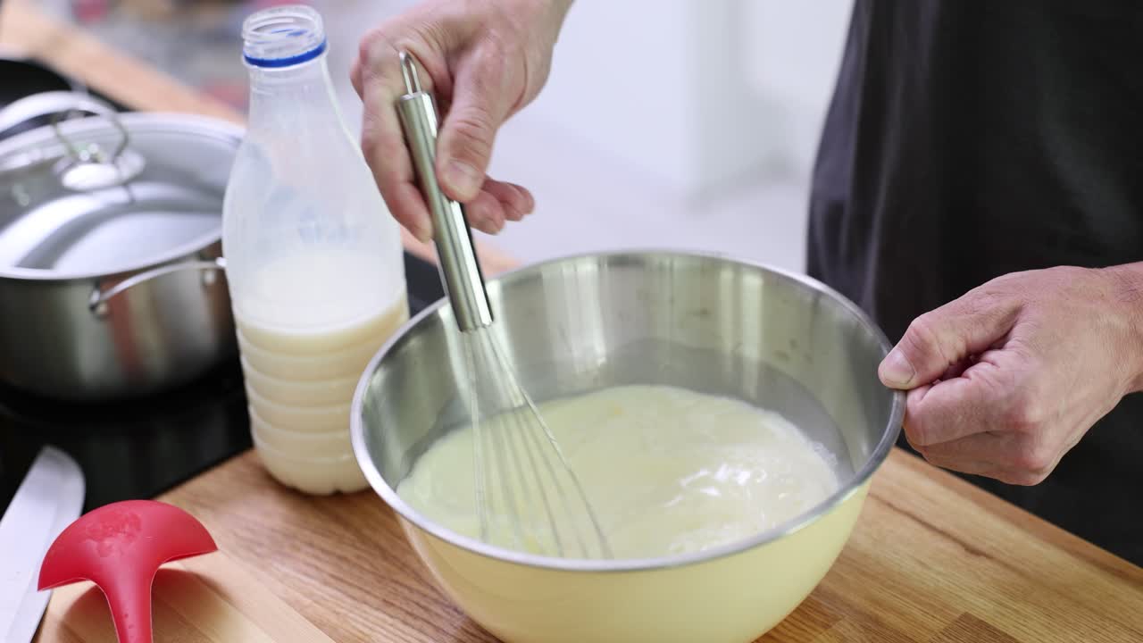 Person mixing ingredients in a bowl with a whisk
