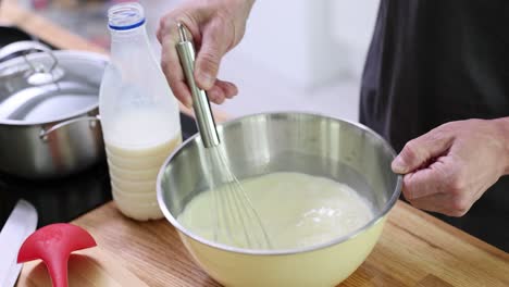 person mixing ingredients in a bowl with a whisk