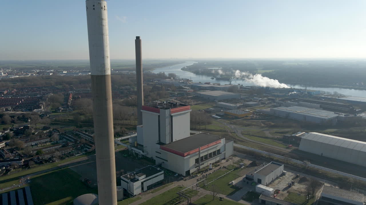 volando más allá de las altas chimeneas del generador de energía en un gran terreno industrial