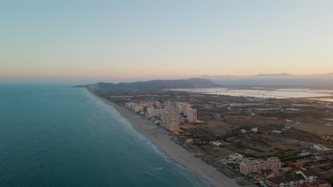 Vista-Aérea-De-Una-Larga-Playa-De-Arena-Con-Edificios-En-La-Costa-De-Cullera-Durante-La-Luz-Del-Atardecer