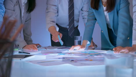 financial analysts strategizing on charts and data during a meeting, discuss bars and graphs, using calculator to analyze data during a business meeting