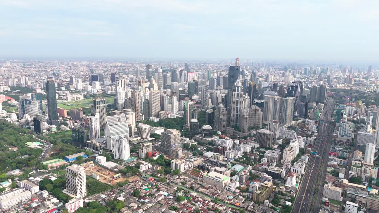Drone view of Bangkok, some skyscrapers, highway and greenery.