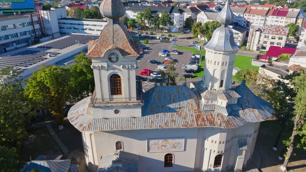 Plano aéreo baixo frontal aproximando-se das torres sineiras da Igreja Uspenia. Ambiente outonal em Botosani, Roménia
