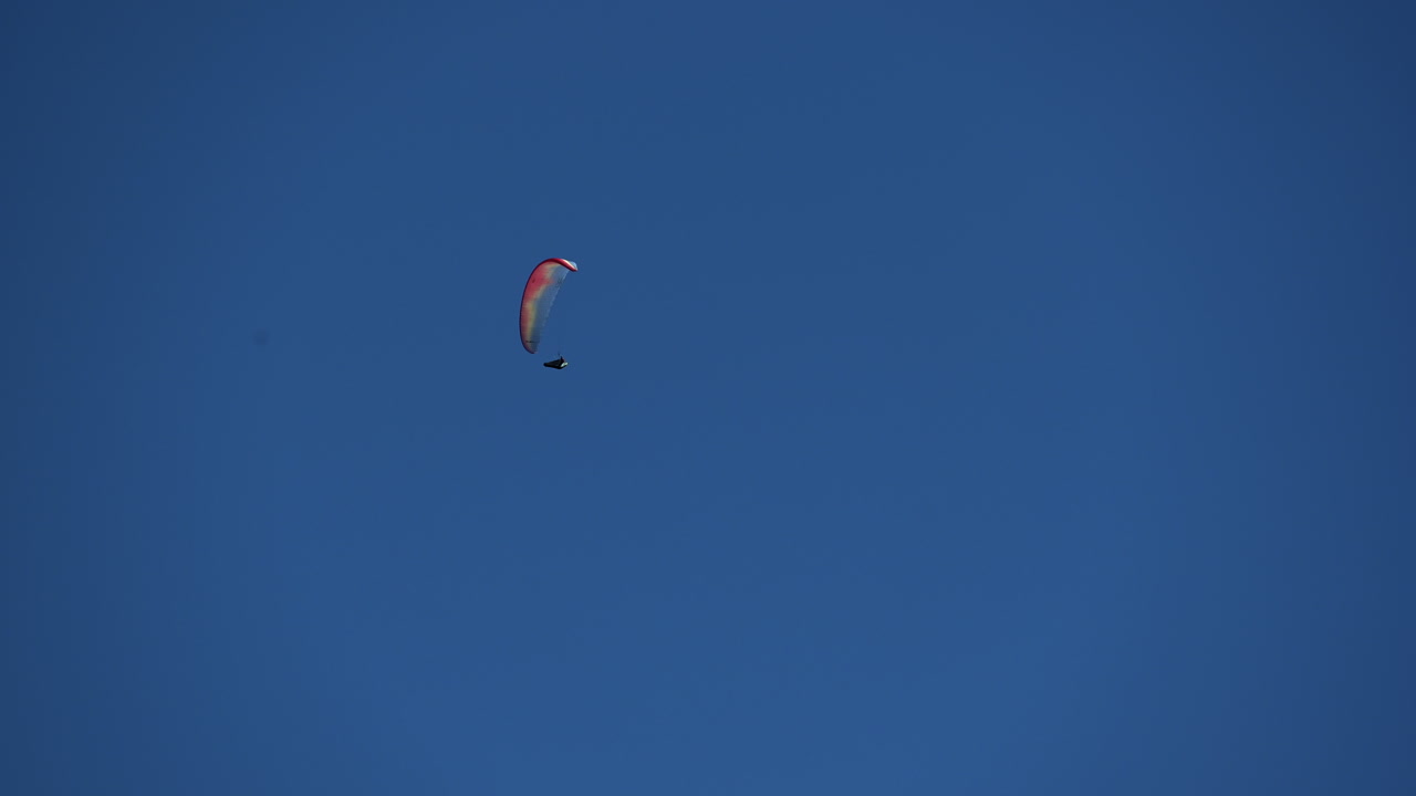 un paracaídas multicolor vuela en el cielo azul sobre los alpes suizos, obwalden