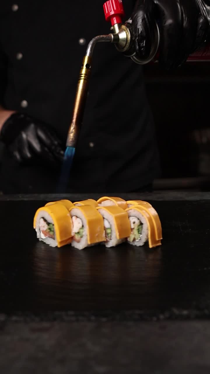 el chef preparando rollos de sushi con queso flameado