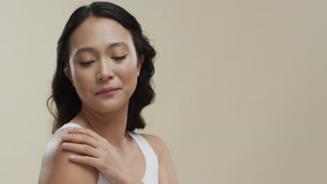 mujer asiática feliz con cabello oscuro en fondo beige con espacio de copia, cámara lenta