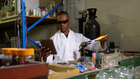 Front-view-of-black-male-worker-using-digital-tablet-while-blowing-glass-in-glass-factory-4k