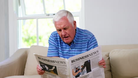 Mature-man-reading-newspapers-on-sofa