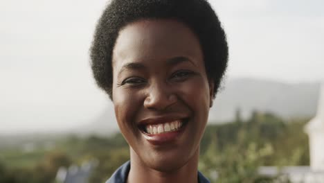 Retrato-De-Una-Feliz-Mujer-Afroamericana-Sonriendo-En-Una-Terraza-Soleada,-Cámara-Lenta