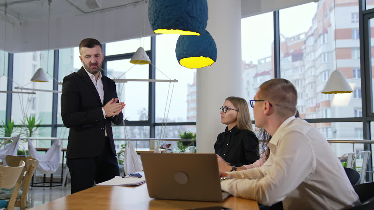 Office employees listen attentively to their boss. Company staff looking at their boss standing in front of them. City background.