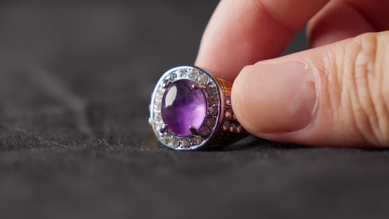 손가락은 가까이에서 아메티스트 반지의 복잡한 세부 사항을 표시합니다.
