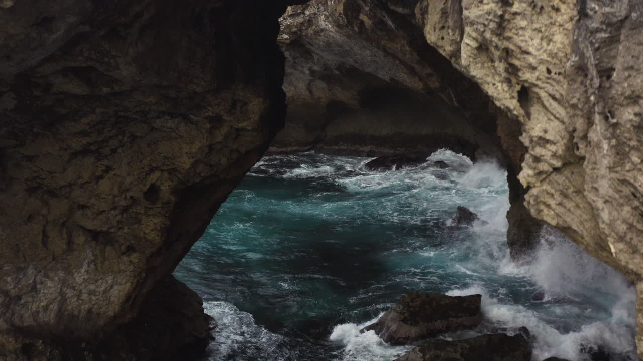 las olas chocan contra las rocas en la cueva del indio en la isla de puerto rico - drone descendiendo