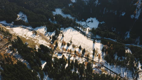 a drone tilted down over a road in a snowy paneveggio park