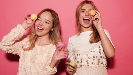 two women holding macarons