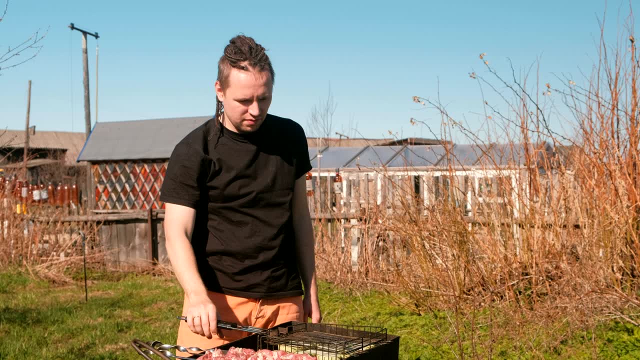 남자가 바베큐 고기 돼지고기와 zucchini를 그릴에 습니다.