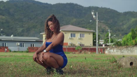 A-young-girl-with-curly-hair,-dressed-in-a-short-blue-dress,-enjoys-a-tropical-park-on-Trinidad-island