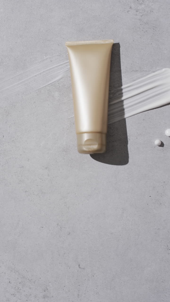Vertical video of beauty product tube and cream smudge with copy space on white background