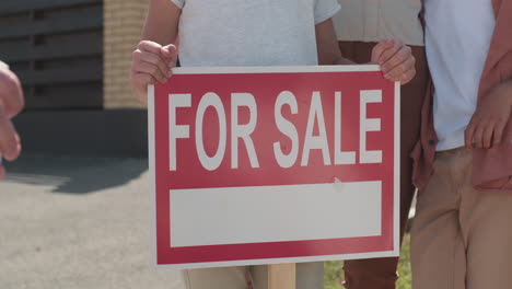 unrecognizable man putting sold on for sale sign