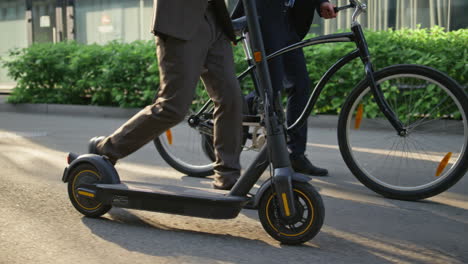 las piernas de los trabajadores pisando la ciudad en primer plano de la mañana. personas corporativas con scooter