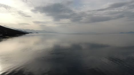 vista de avión no tripulado en albania volando sobre el lago shkoder en pogradec en un día nublado con montañas sombrías en el horizonte