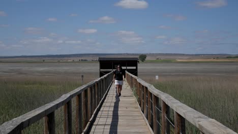 a person walking on a wooden path leading into a scenic natural reserve