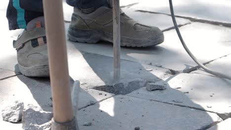 worker using jackhammer to break paving stones