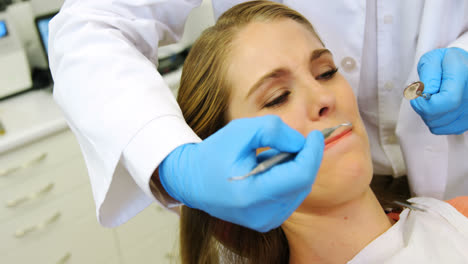 dentistas examinando a una paciente femenina con herramientas