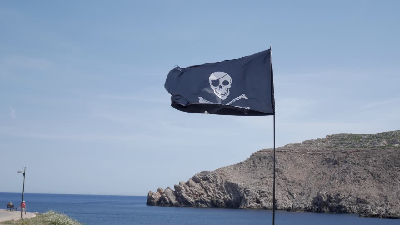 Pirate flag waving by the sea in Fornells, Menorca, evoking adventure and mystery