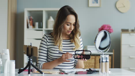 pretty beauty blogger recording a makeup tutorial video and teaching how to apply eyeshadows