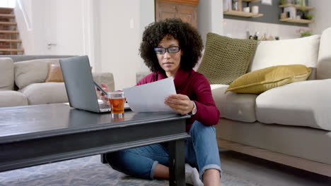 happy biracial woman using laptop and smartphone at home, slow motion