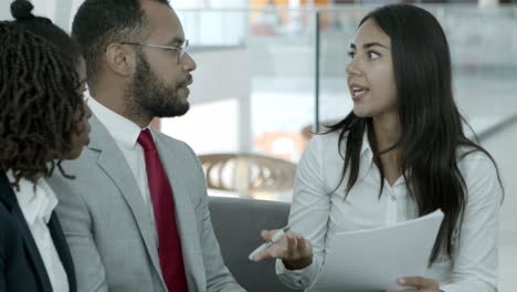 Businesswoman-holding-papers-and-talking-with-coworkers